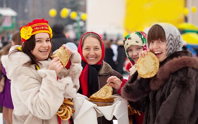 Women eating pancakes during  Maslenitsa